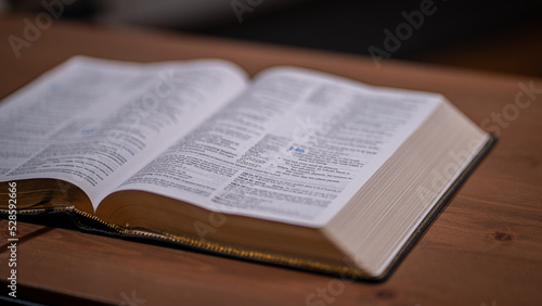 Open book (Bible) on a wooden table with white pages and space for text