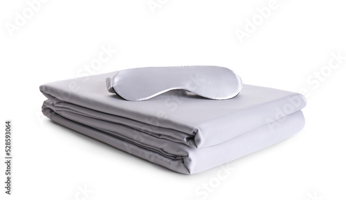 Stack of clean silky bed linen and sleeping mask isolated on white