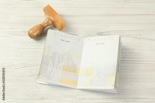 Moldova, Ceadir-Lunga - June 13, 2022: Wooden stamp and open passport with blank visa pages on white table photo