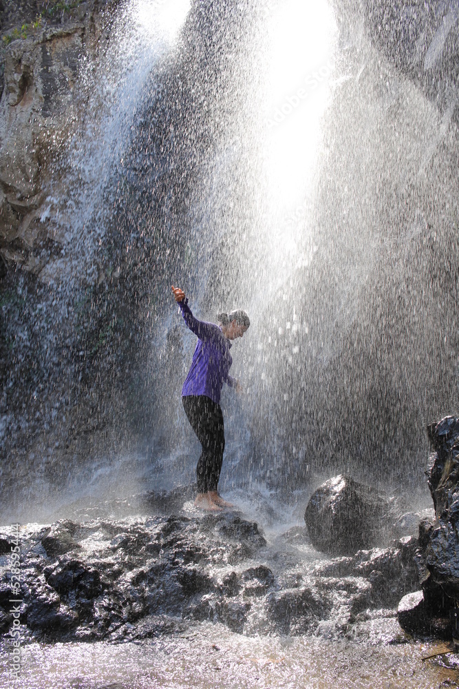 Fototapeta premium Mujer disfrutando la naturaleza bajo cascada en la montaña senderismo aventura aire libre climbing 
