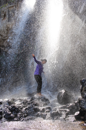 Mujer disfrutando la naturaleza bajo cascada en la montaña senderismo aventura aire libre climbing 