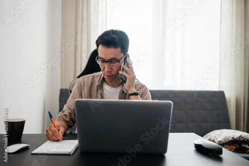 Middle aged asian man working at home with laptop.