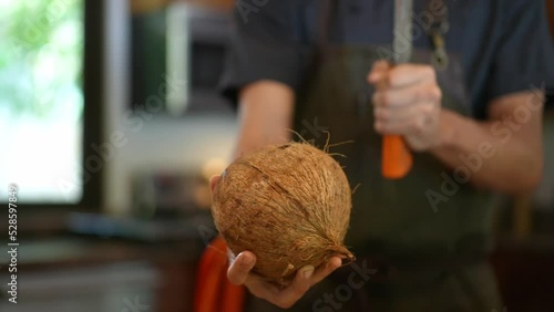 caucasian young chef preparing healthy fresh food in the kitchen. Slow motion 4k. man cuts coconut to prepare coconut milk. organic healthy ingredients for gourmet dish. 