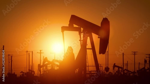 The sun rises behind oil pumps in California