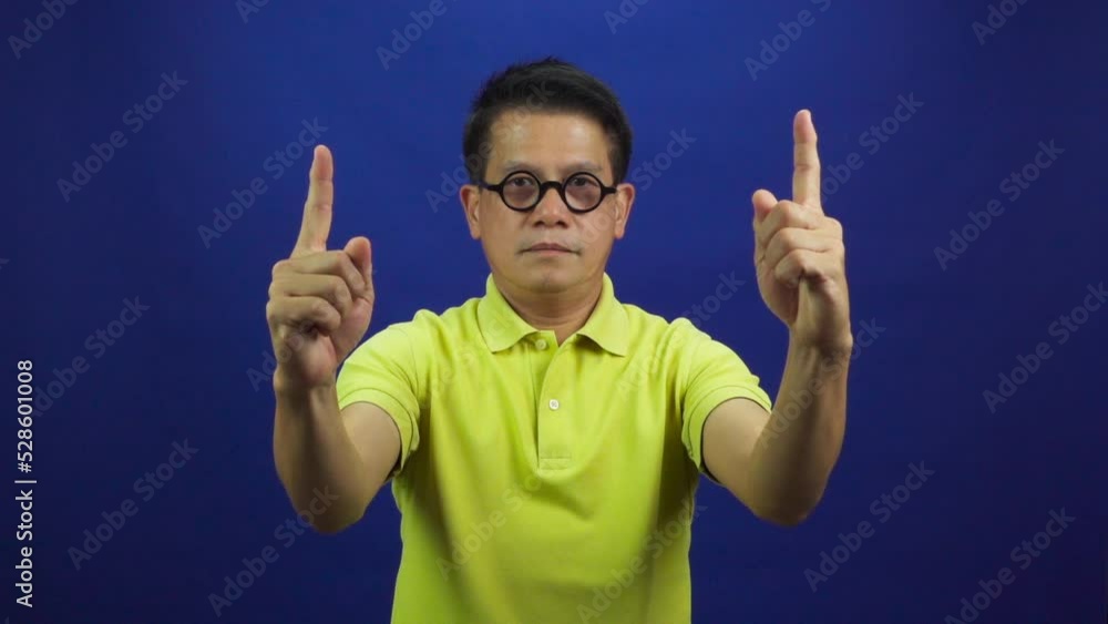 Portrait of smiling middle-aged asian man in casual yellow polo shirt pointing fingers up isolated on blue background in studio, looking happiness and attractive professional leadership Portrait of smiling middle-aged asian man in casual yellow polo shirt pointing fingers up isolated on blue background in studio, looking happiness and attractive professional leadership
