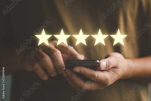 Fotografia close up Woman hand using smart phone and give five star symbol to increase rating of product and service concept, Customer service experience and business satisfaction survey