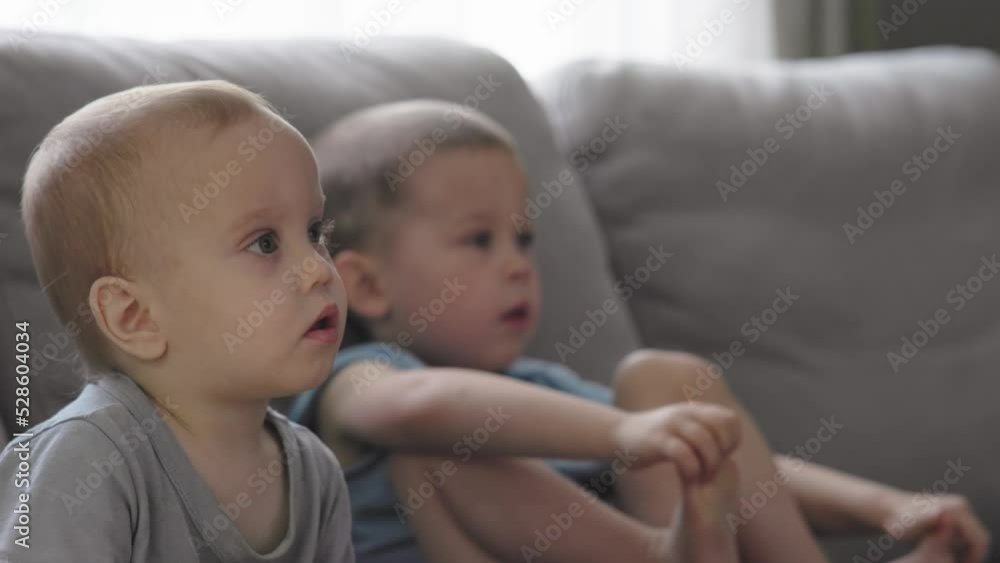 two baby boys children watching tv at home hypnotized attentively keen staring at screen two baby boys children watching tv at home hypnotized attentively keen staring at screen