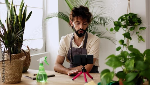 Small business entrepreneur owner of plant shop streaming online from workplace. Young adult content creator influencer blogger recording a video talking about indoor plants care photo