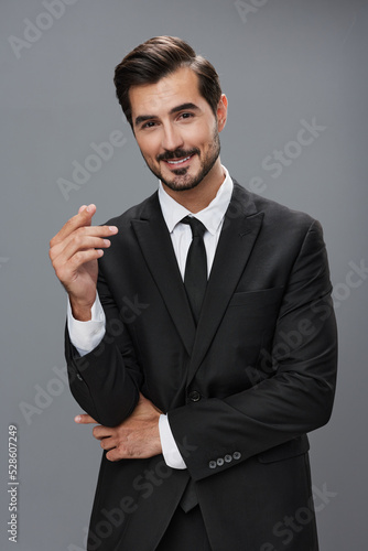 Stylish young man in a brunette business suit posing on a gray background and smiling businessman