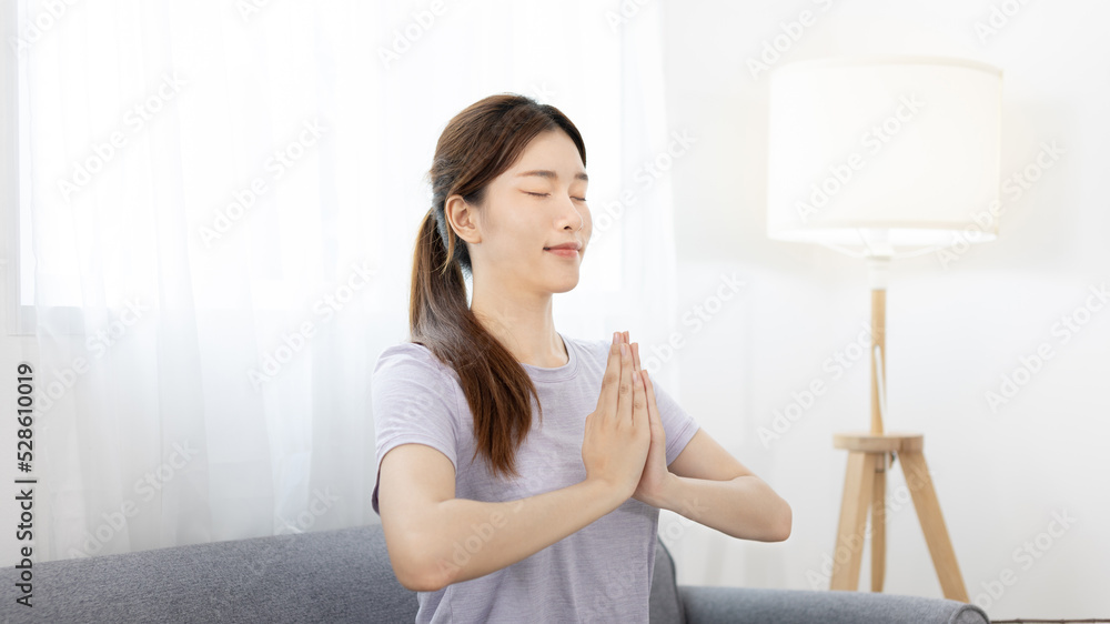 Beautiful young woman in sportswear is meditating or yoga and breathing on the sofa, Body and mind health care, Relaxation through meditation, Healthy exercise, Quiet living room. Beautiful young woman in sportswear is meditating or yoga and breathing on the sofa, Body and mind health care, Relaxation through meditation, Healthy exercise, Quiet living room.