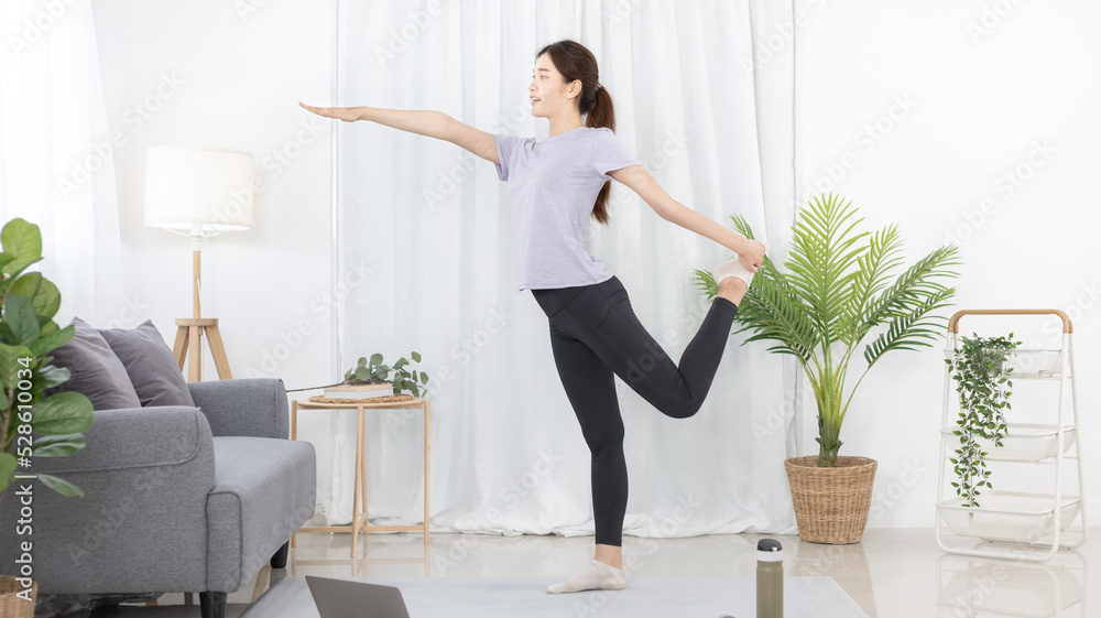 Beautiful Asian woman in sportswear is warming up or doing light exercises in the house with dumbbells and a protein shake or bottle of water and using a laptop at home, Healthy exercise. Beautiful Asian woman in sportswear is warming up or doing light exercises in the house with dumbbells and a protein shake or bottle of water and using a laptop at home, Healthy exercise.