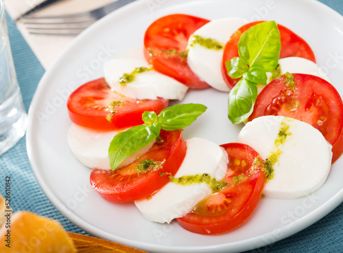 Caprese salad with fresh tomatoes, mozzarella cheese and basilic herb, dish of Italian cuisine