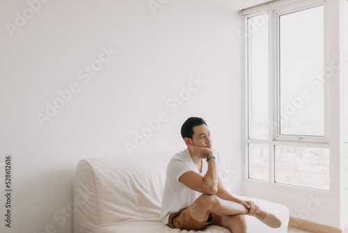 Bored and lonely asian man with his spare time to waste in his apartment.