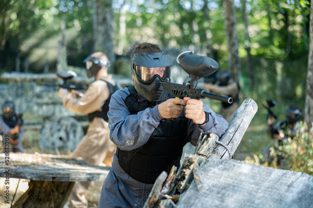 Fototapeta premium Paintball player recklessly aims with a gun on the battlefield