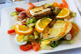 Healthy salad with grilled goat cheese, oranges, cucumbers, tomato, honey and balsamic sauce