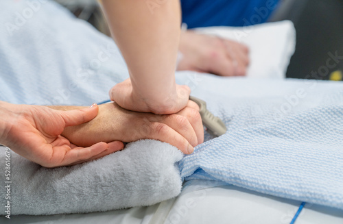 Hand holding the hand of a loved one dying in hospital