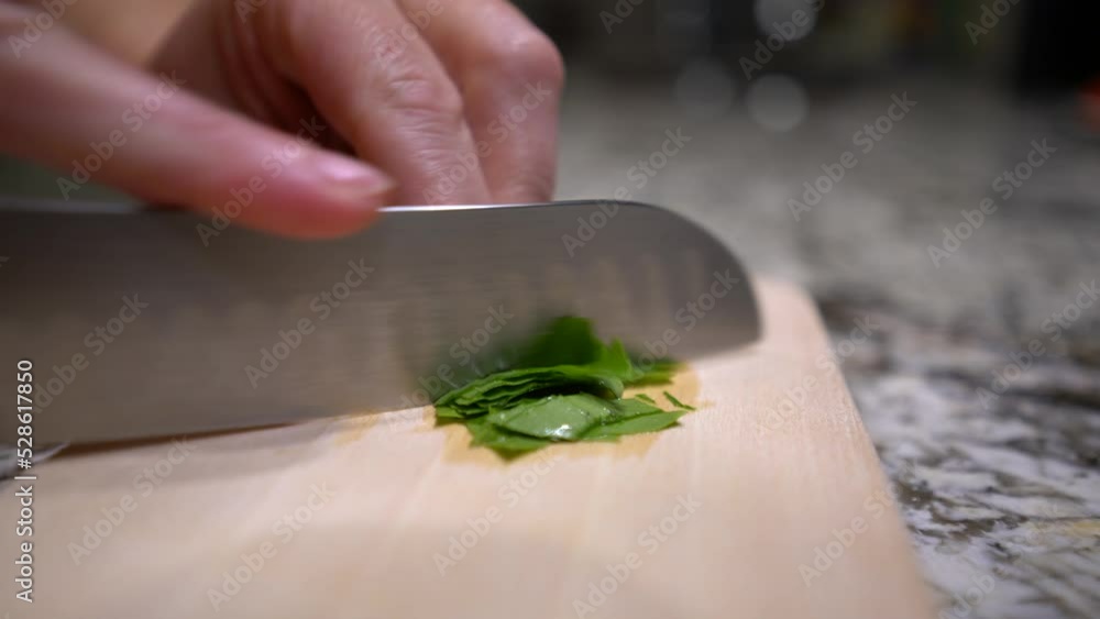 Careful cutting of basil leaves with hollow edge santoku knife, detail shot Careful cutting of basil leaves with hollow edge santoku knife, detail shot