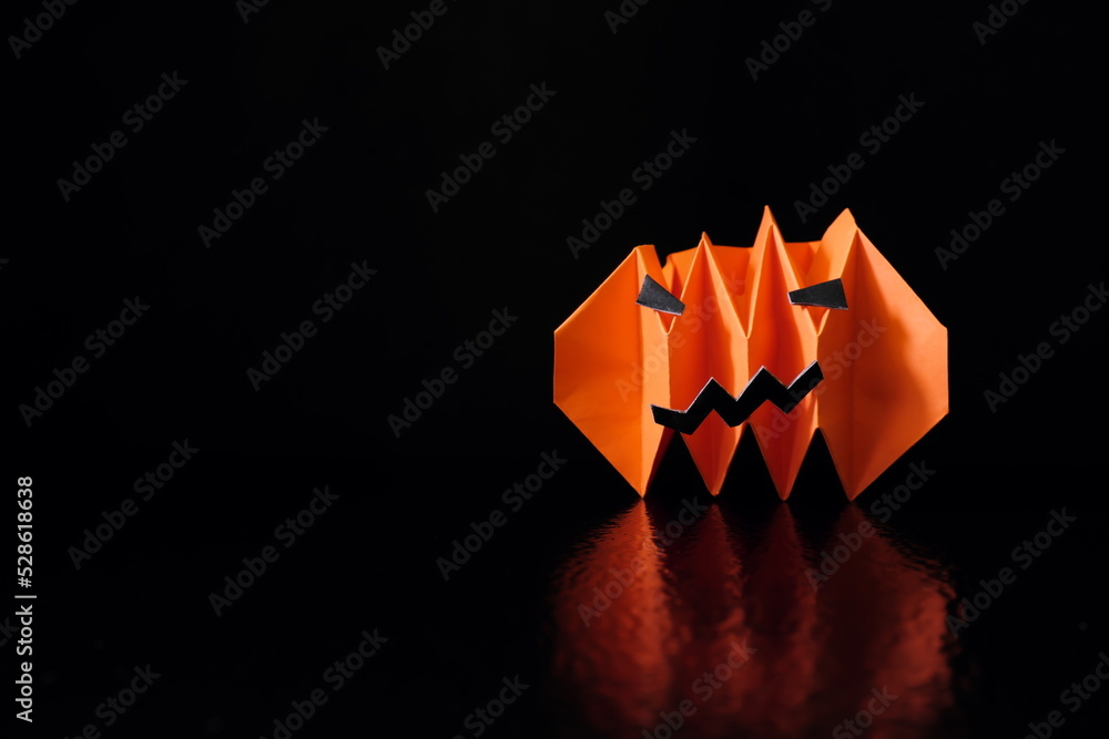 Fototapeta premium Halloween concept. Scary pumpkin or jack o lantern paper craft on dark black background with copy space.