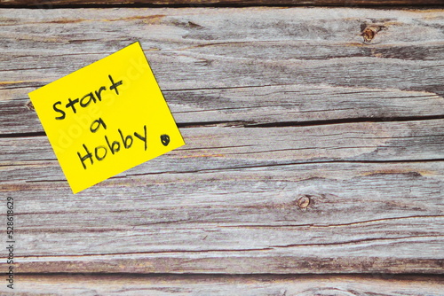 Start a hobby for a healthy lifestyle and wellbeing concept. Yellow sticky note reminder in wooden background with copy space.