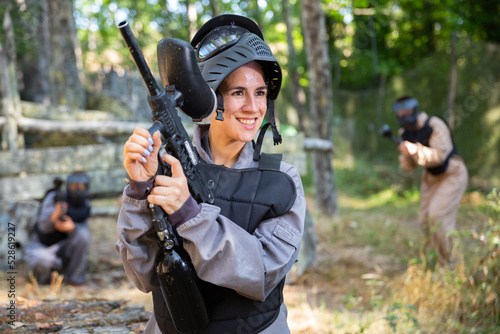 Portrait of pleased woman in uniform with paintball gun