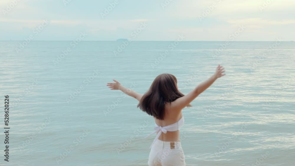 Beautiful Asian woman raising arms and enjoying freedom turn around at tropical paradise beach, Happy female in bikini swimsuit having fun open arms in summer vacation travel Beautiful Asian woman raising arms and enjoying freedom turn around at tropical paradise beach, Happy female in bikini swimsuit having fun open arms in summer vacation travel