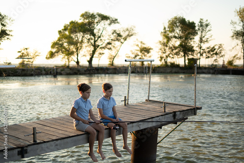 Boys fishing at sunset on the lake. Summer hobby and leisure