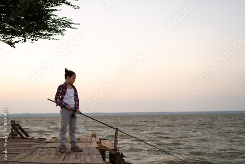 Boy fishing on the lake at sunset. Child fishing spinner rod in summer.