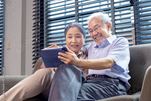фотографія Senior Asian couple in retirement age looking at nostalgic photo using digital t