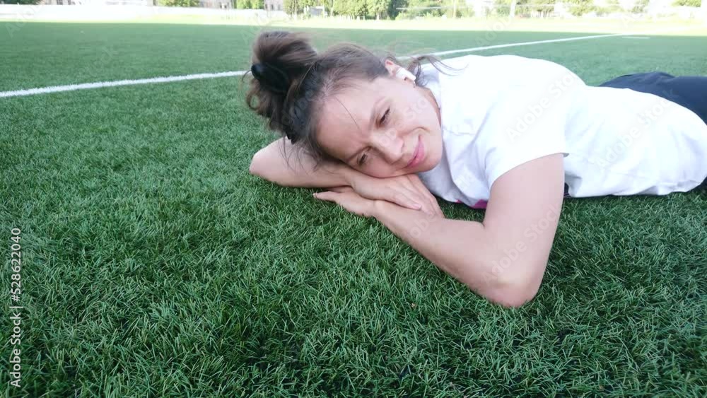 Beautiful girl lying on the green grass and listening music by headphones Beautiful girl lying on the green grass and listening music by headphones