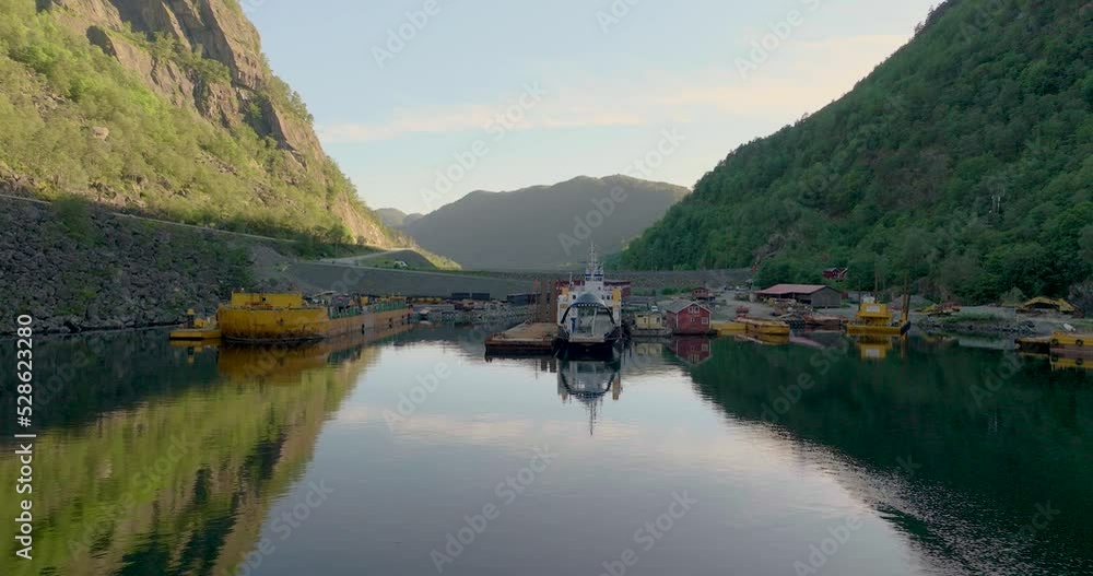 Norwegian car ferry docked at industrial harbor for reparations, flat calm water in fjord, aerial Norwegian car ferry docked at industrial harbor for reparations, flat calm water in fjord, aerial
