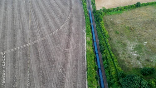 Drone shot of a blue train on a tree lined railway going through British countryside photo