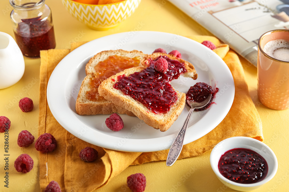 Plate with tasty toasts, apricot and raspberry jam on yellow background, closeup Plate with tasty toasts, apricot and raspberry jam on yellow background, closeup