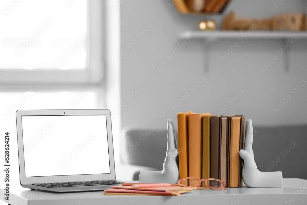 Stylish holder with books, eyeglasses and laptop on table in room Stylish holder with books, eyeglasses and laptop on table in room