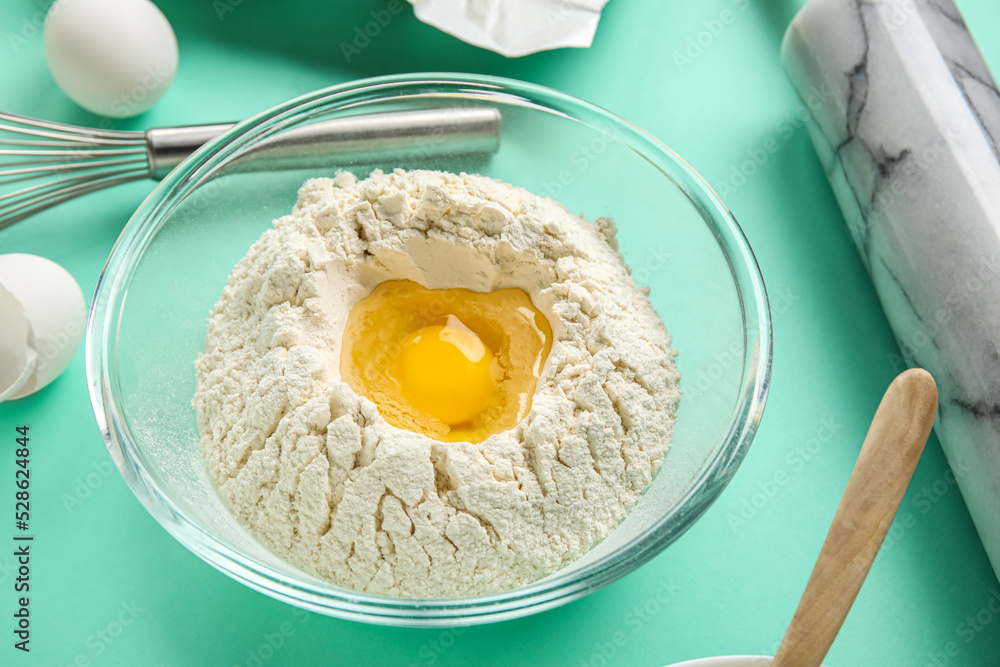 Glass bowl of flour with egg on color background, closeup Glass bowl of flour with egg on color background, closeup