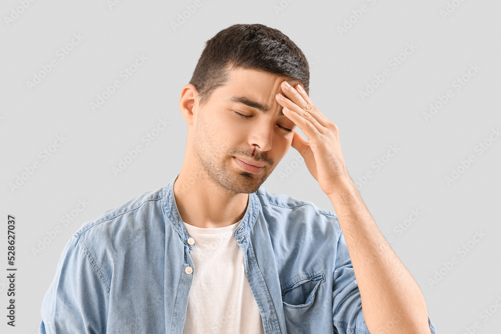 Young man with nosebleed on light background, closeup Young man with nosebleed on light background, closeup