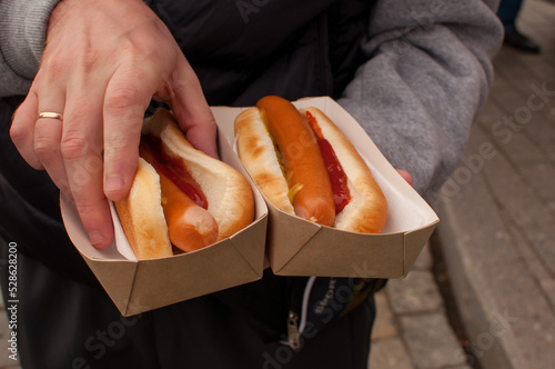 two hot dogs in a cardboard box in the man's hand