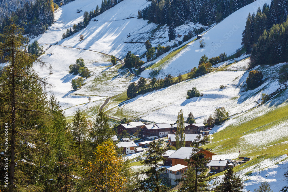 Village in an alps valley with snow on the fields