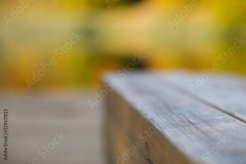 wooden bench in park close-up against background of yellow autumn leaves