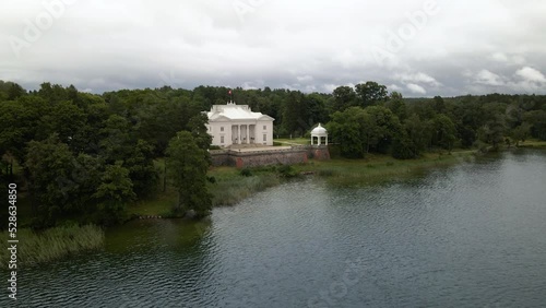 Aerial shot of the Uzutrakis Manor House in Trakai, Lithuania near Galves lake surrounded by green lush trees photo