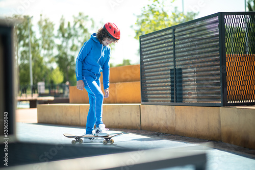 Fototapeta Pleased teenage boy getting on the skateboard