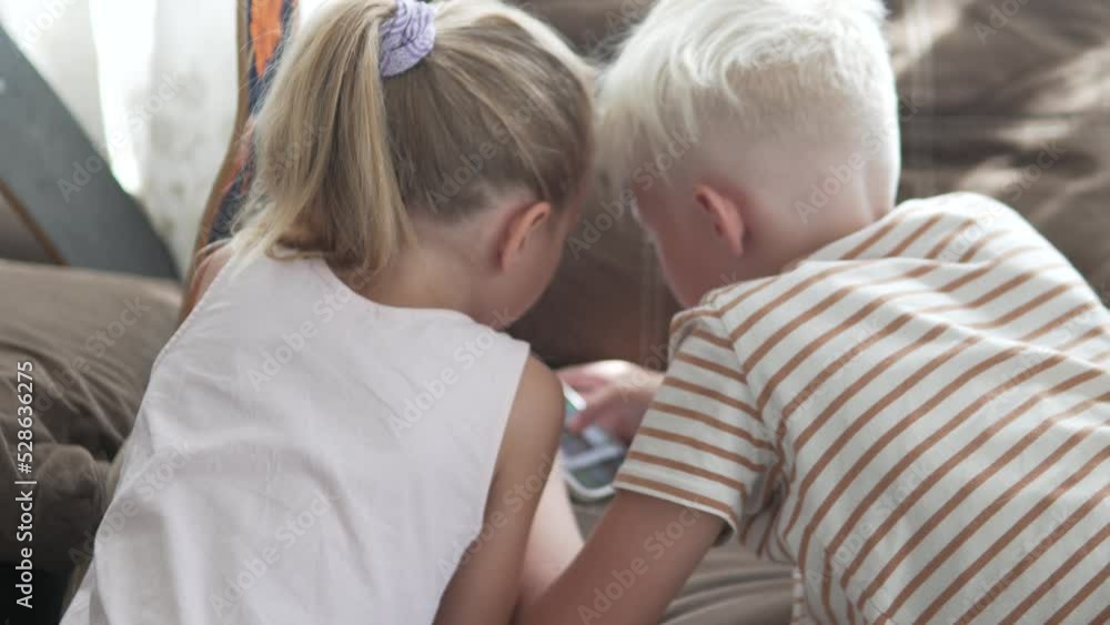 Children are staring at the phone, children are surfing the Internet at home from the phone. Children are staring at the phone, children are surfing the Internet at home from the phone.