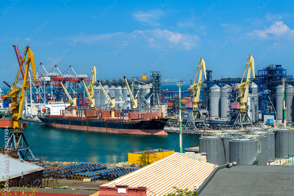 industrial seaport infrastructure, sea, cranes and dry cargo ship, grain silo, bulk carrier vessel and grain storage elevators, concept of maritime cargo transportation