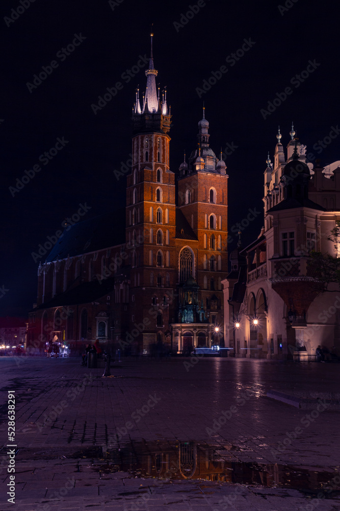 St. Mary's Basilica in Krakow with reflection in a puddle at night | Bazylika Mariacka w Krakowie z odbiciem w kałuży nocną porą