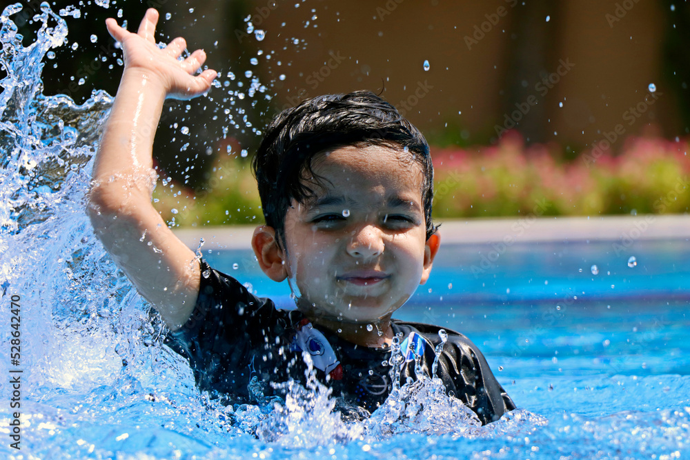 Fototapeta premium young boy enjoying in swimming pool, water splashing