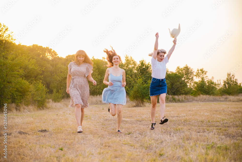 A group of girlfriends jumps and runs outdoors. A group of female friends hugs and enjoys the sunset in nature. Laughter, smiles and joy. A group of girlfriends jumps and runs outdoors. A group of female friends hugs and enjoys the sunset in nature. Laughter, smiles and joy.