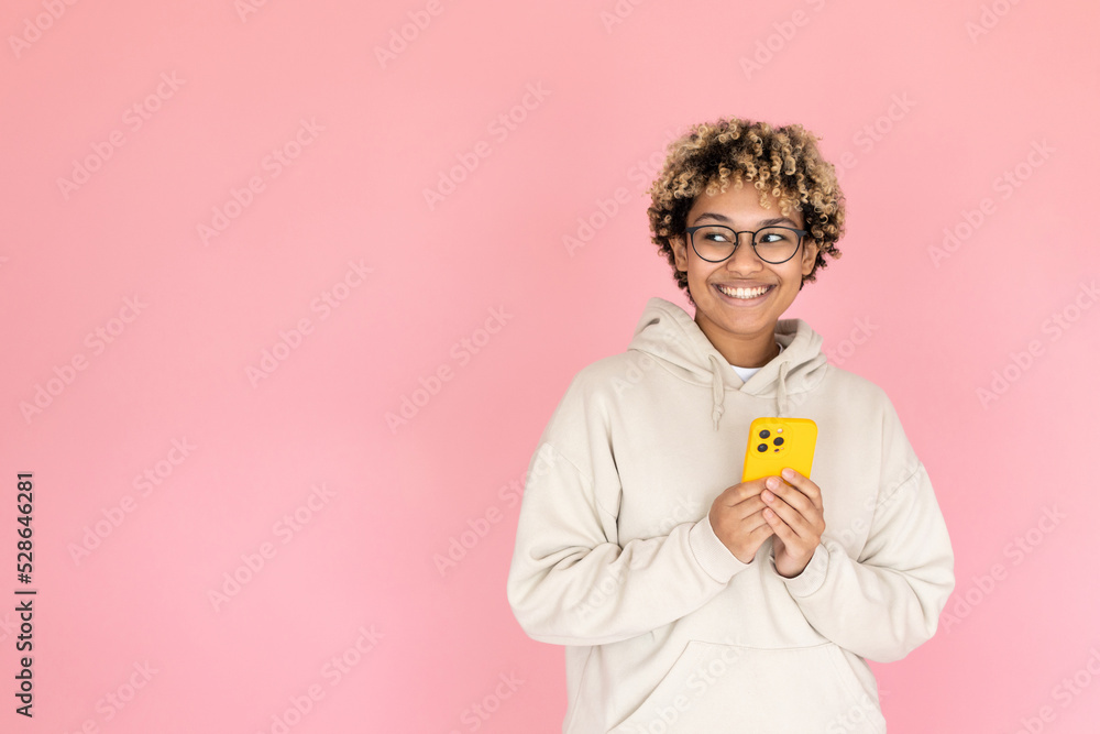 Smiling African American woman with phone. Female model in glasses with curly hair holding mobile phone in studio. Portrait, studio shot, emotion concept Smiling African American woman with phone. Female model in glasses with curly hair holding mobile phone in studio. Portrait, studio shot, emotion concept