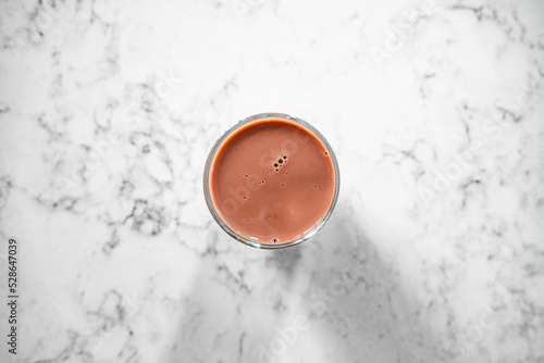 Glass of chocolate milk. Top down view into glass. Marble counter top