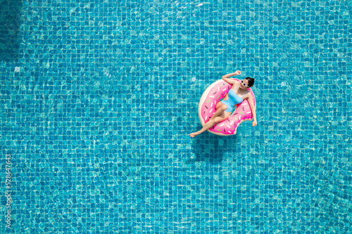 Valokuva Top view of young asian woman in swimsuit on the pink donut lilo in the swimming pool