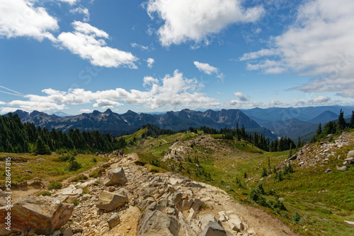 The skyline trail surrounded by a landscape of mountains, forests, and a cloudy blue sky at Mt. Rainier National Park.