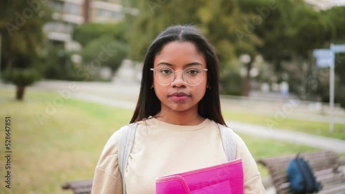 Serious hispanic teen standing outdoors at university capus looking at camera with his googles. Portrait of pretty school girl. High quality 4k footage photo